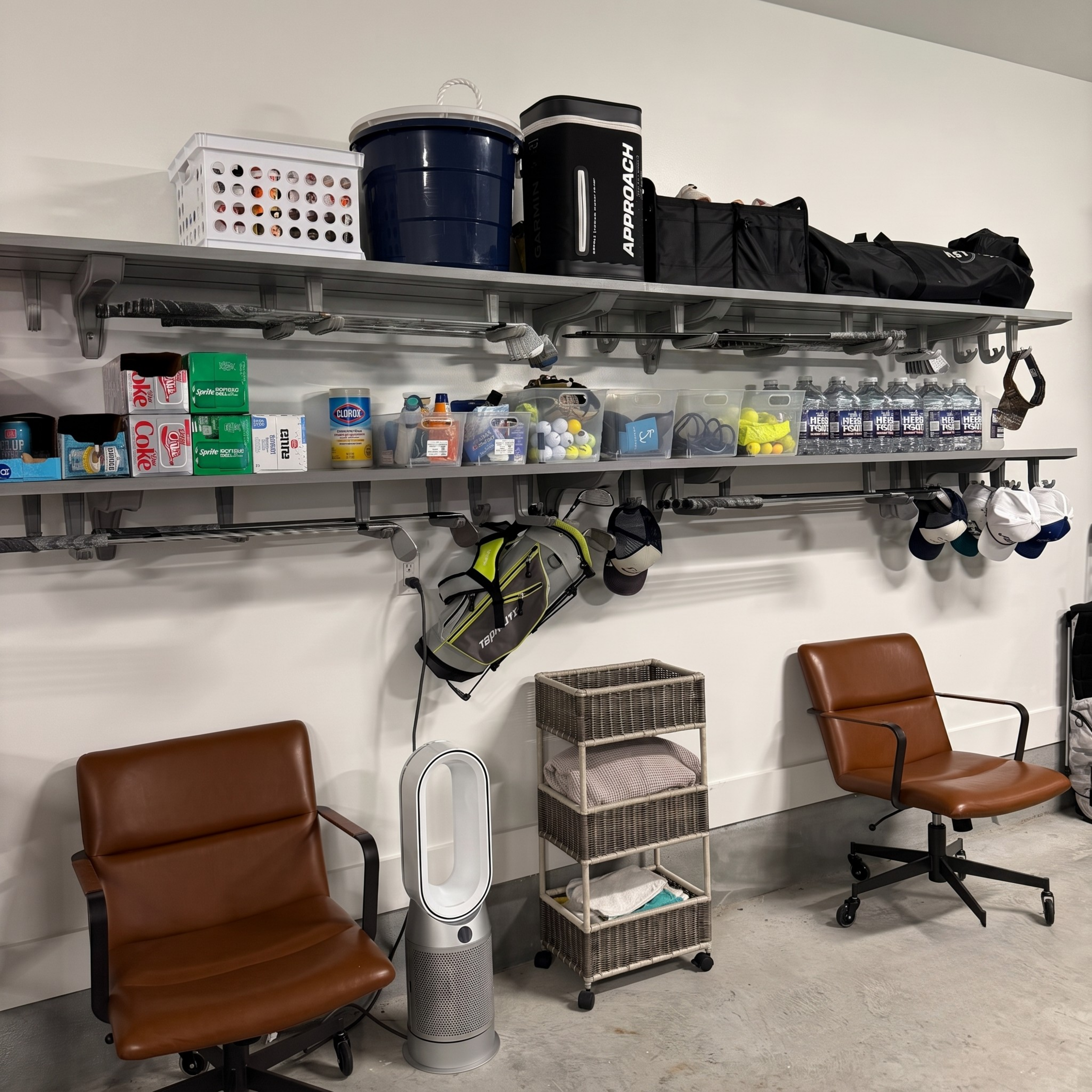 A storage room setup with two brown office chairs, metal wall shelves holding bins, bags, and supplies, and a tall silver floor vent in the center.