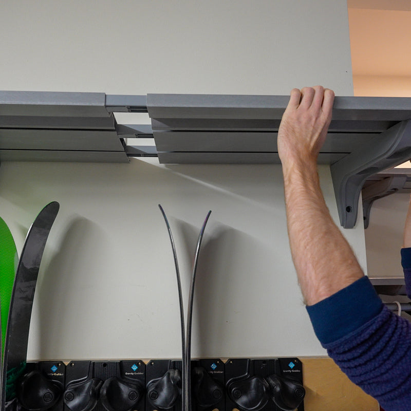 Hands sliding a new shelf section onto extension sleeves to extend an installed run of extendable shelving