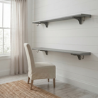 Toden gray modular double-row shelving system configured as a floating desk and upper storage shelf on a white shiplap wall. The setup features two long-run gray panels supported by industrial-strength brackets with integrated snap-fit hooks. The "no diagonal support" design highlights maximum legroom and a sleek, modern aesthetic for a home workspace or study area.