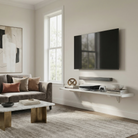 Toden white modular surface used as a minimalist floating TV console in a modern living room. The heavy-duty 72-inch shelf is mounted beneath a wall-mounted television and soundbar, holding a game console, books, and decor. The setup highlights the sleek "no diagonal support" design and industrial load capacity, providing a clean, cable-managed media storage solution.