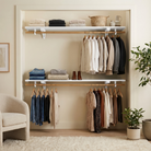 An open closet organizer with two wooden shelves and multiple hangers holding folded and hanging clothing, shown in a styled room with a chair, rug, and potted plants.