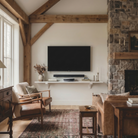 Toden white modular surface used as a sleek floating TV console in a modern rustic living room. The heavy-duty shelf is mounted on a neutral wall beneath a flat-screen TV and soundbar, nestled between a stone fireplace and exposed wood beams. The setup showcases the system's "Modern Form" and high-capacity load rating, providing a minimalist media storage solution that complements warm, natural interior textures.
